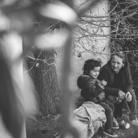 CHIRYO Outcomes and Intervention Services female staff and boy child outdoor sat on log